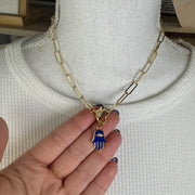 Gold chain necklace with blue Hamsa charm styled on model