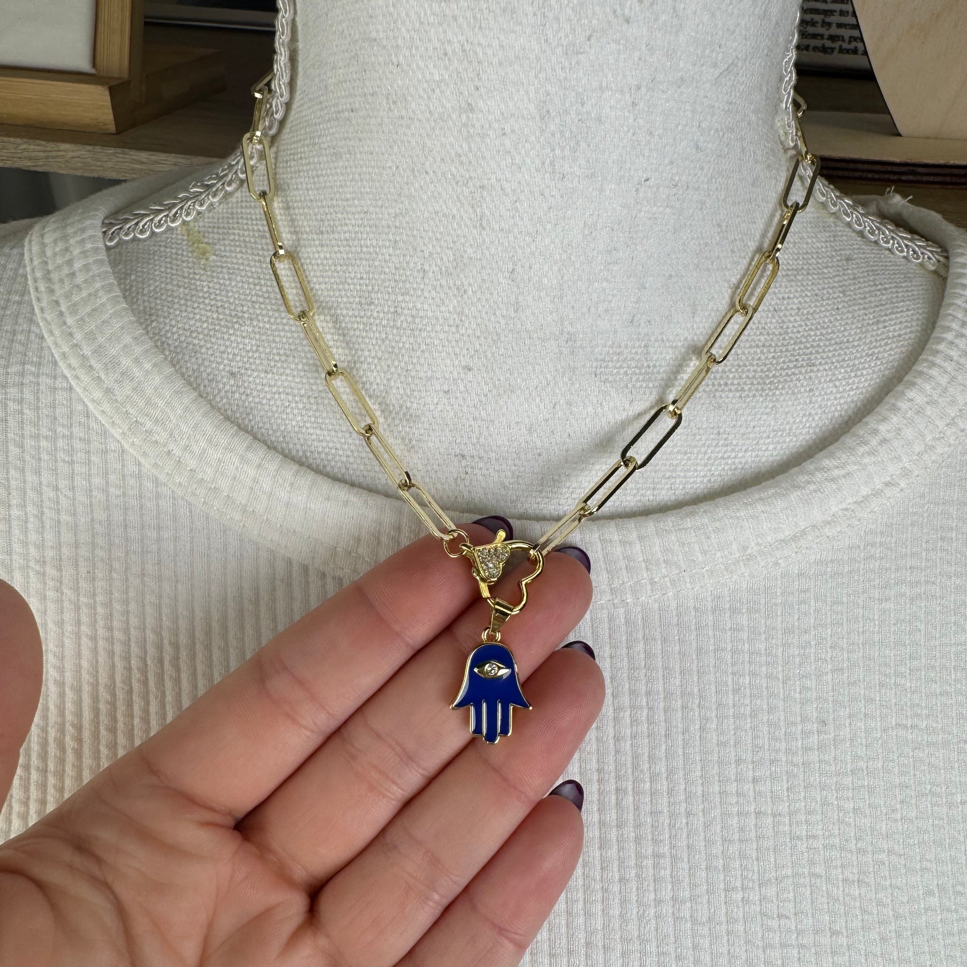 Gold chain necklace with blue Hamsa charm styled on model