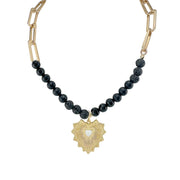 Necklace with black beads and a gold heart pendant on a white background