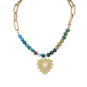 A gold chain necklace with multicolored gemstone beads and a gold charm in the shape of a hand with a heart cut out in the center.