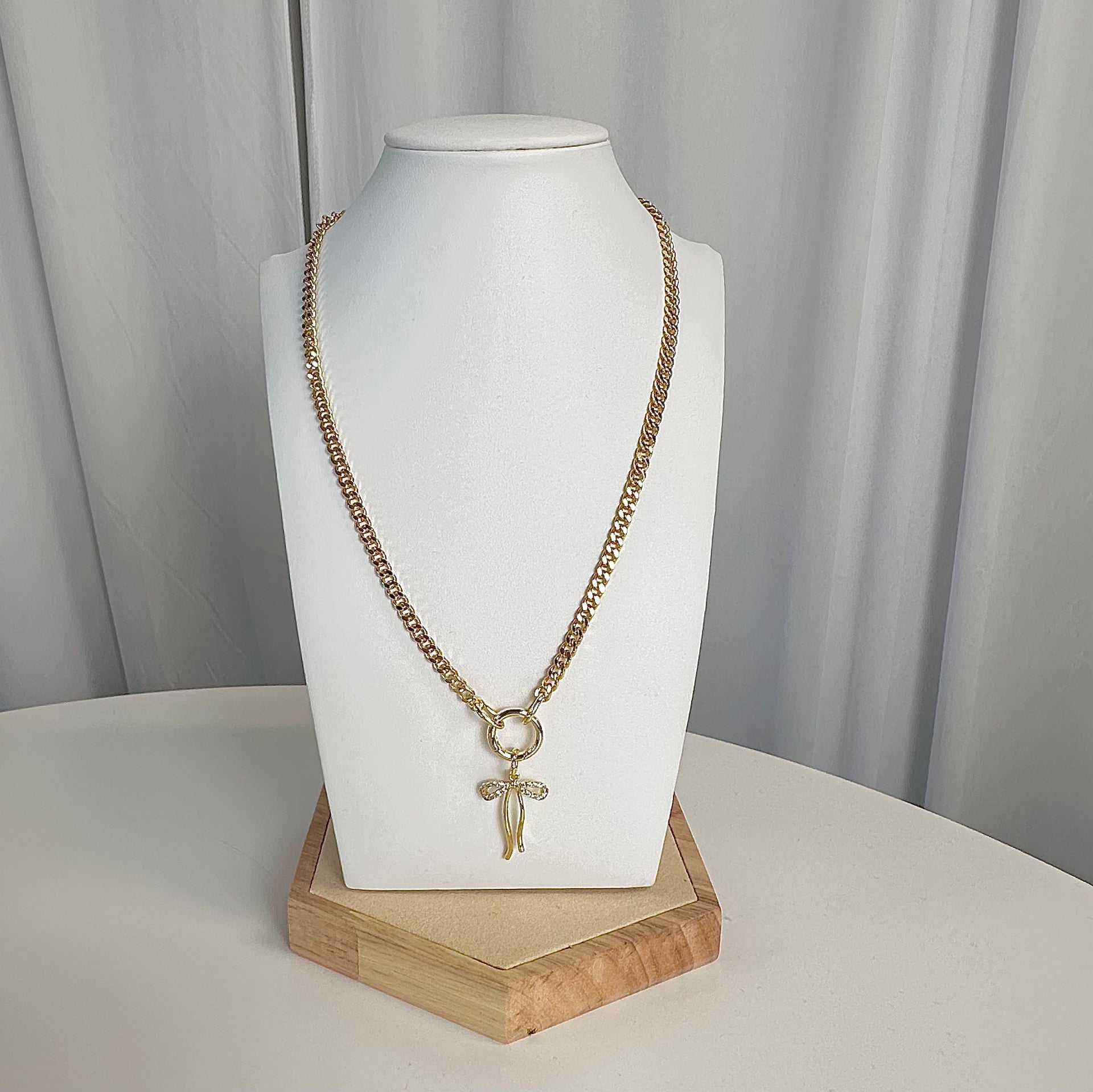 Mariano Clasp Charm Necklace in gold with bow charm on display by Love Lisa