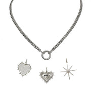 A silver curb chain necklace with a polished round clasp and three charms including a heart, a spiky heart, and a star.