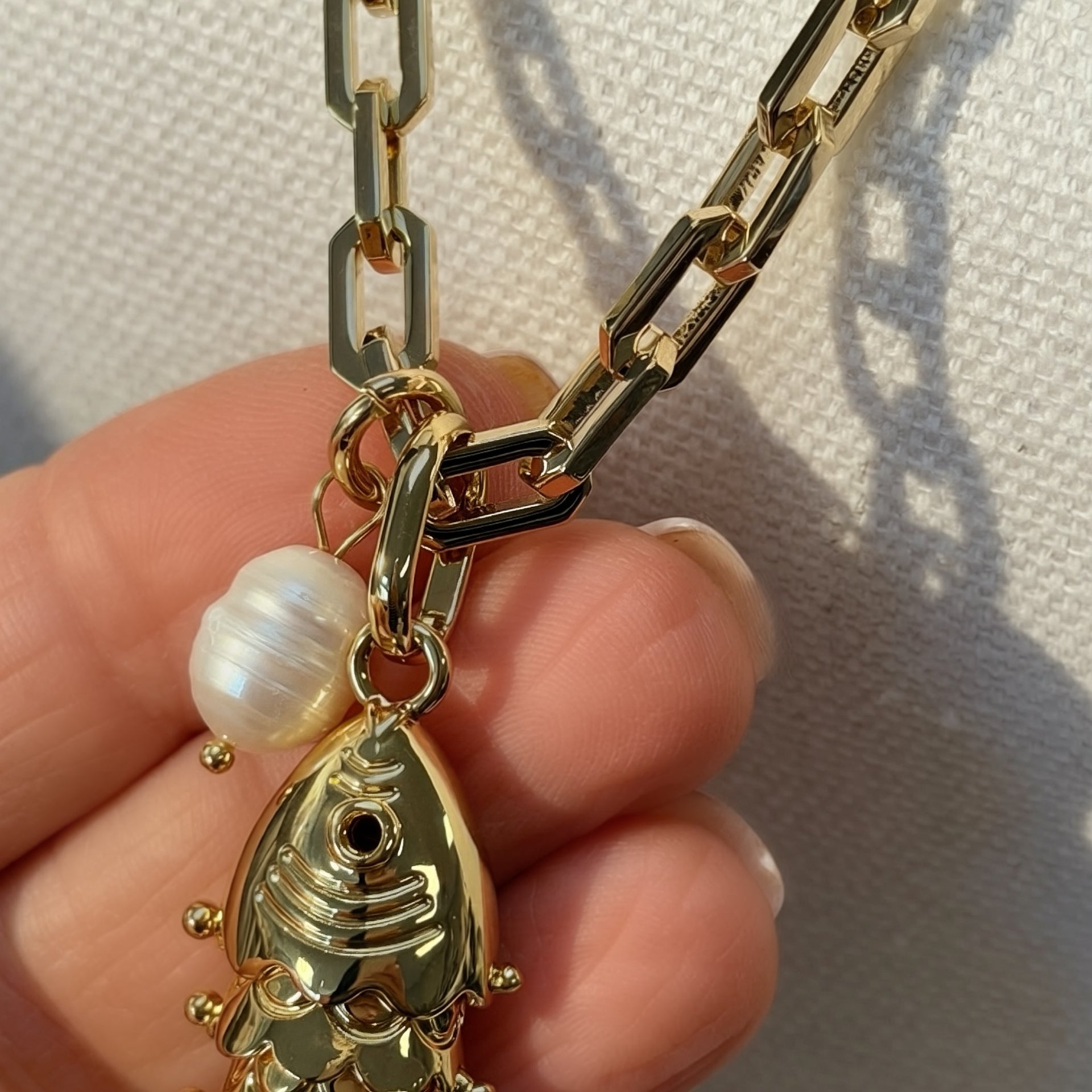 Love Lisa Maris Pearl Fish Charm Necklace close up showing polished gold paperclip chain freshwater pearl accent and detailed fish charm