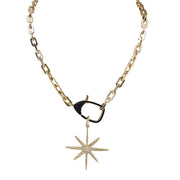 Gold necklace with black north star pendant on a white background