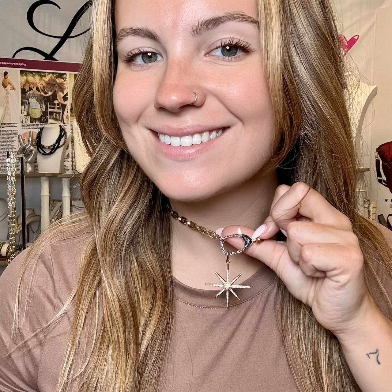 Woman holding a necklace with a star pendant in front of a store display.