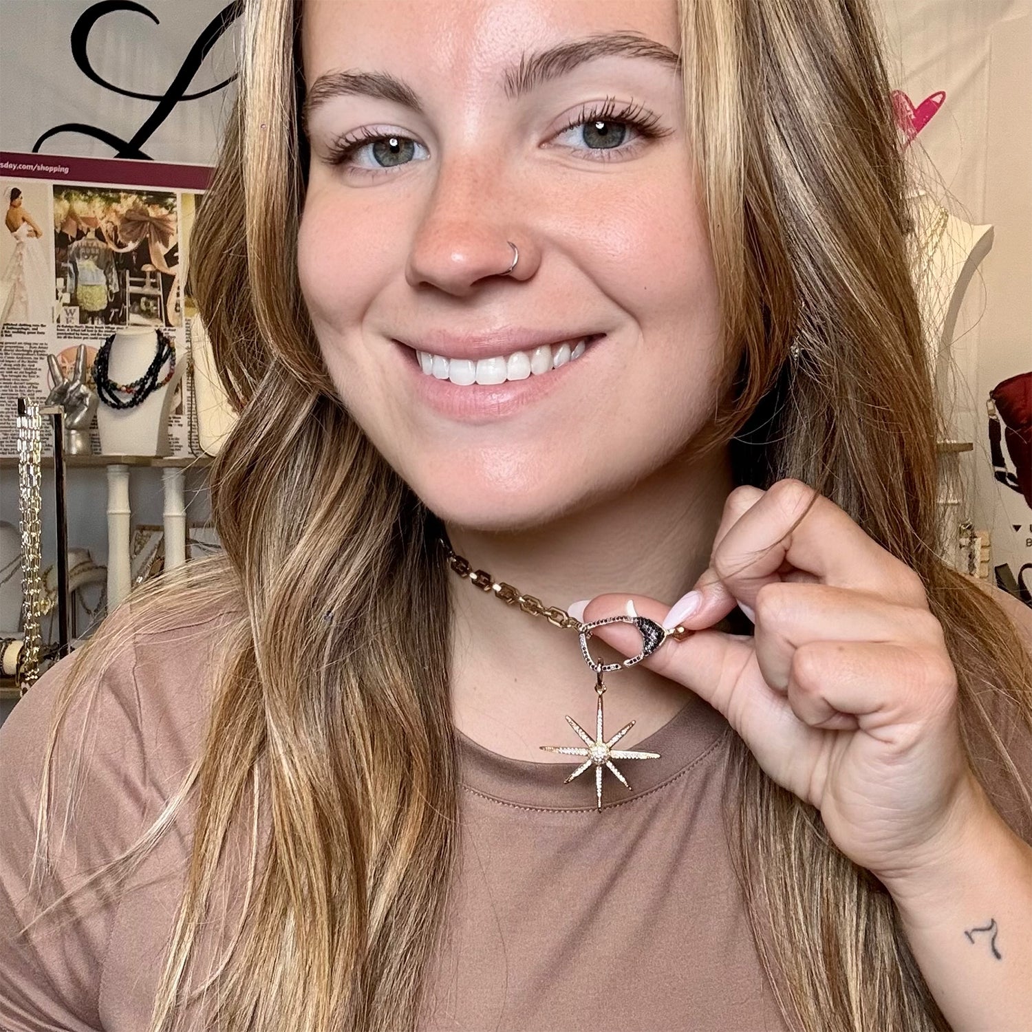 Woman holding a necklace with a star pendant in front of a store display.