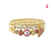 Love Lisa Meghan Breast Cancer Awareness WARRIOR Bracelet Stack with gold-tone beads, pink pavé evil eye bracelet, slanted heart bracelet, and WARRIOR detail