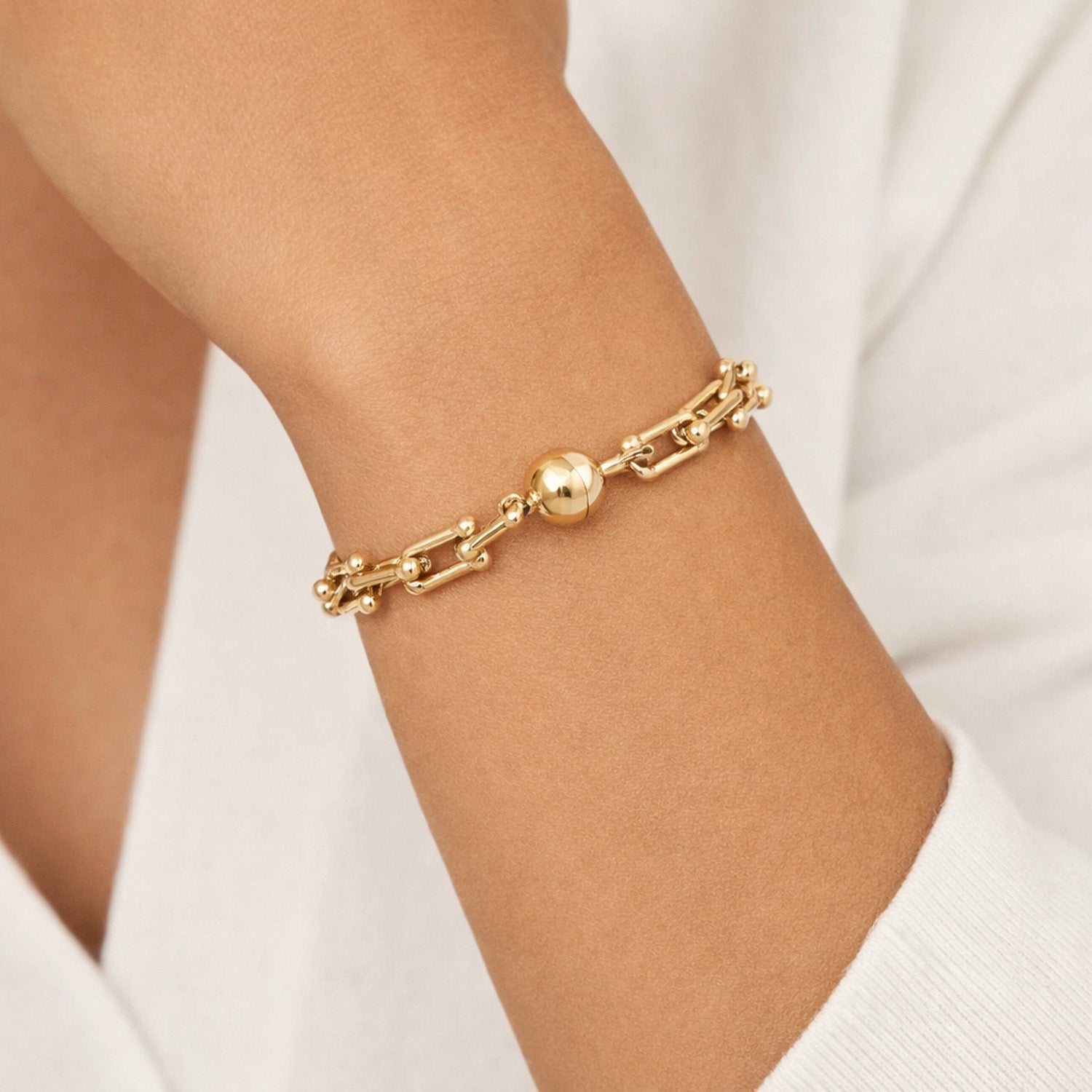Mila magnetic link bracelet gold worn on wrist with polished gold chain and magnetic clasp on white background