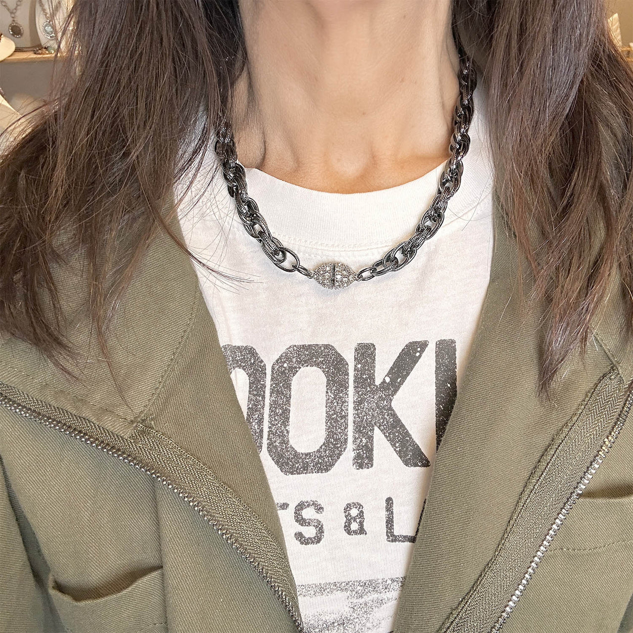 A gunmetal chain necklace with textured links and a pavé crystal magnetic clasp on model