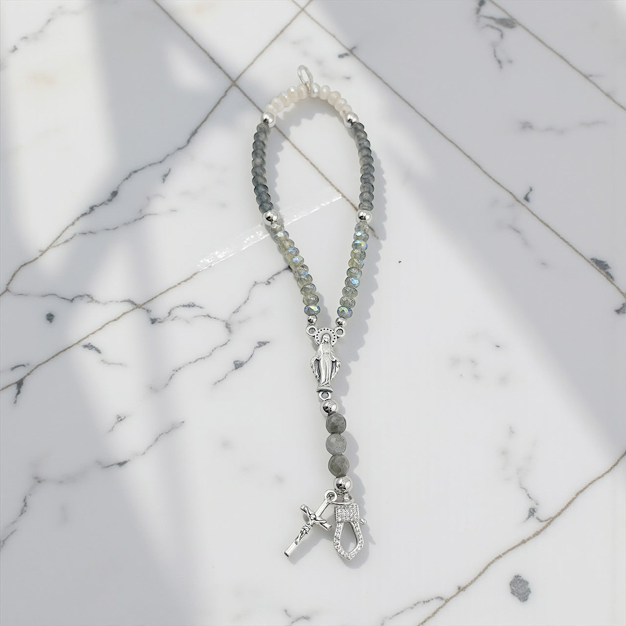Rosary inspired Catholic stretch bracelet in grey and silver  featuring Miraculous Medal and cross charms shown unclasped 