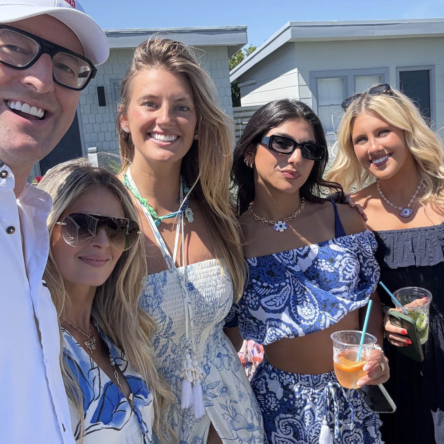 Group of models wearing love lisa jewelry posing outdoors, enjoying drinks and each other's company.