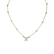 A pearl necklace with a gold chain and a silver initial charm in the shape of the letter 'A'.