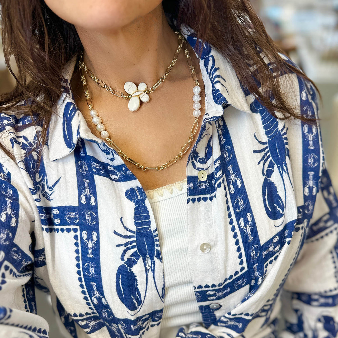 Person wearing a blue and white patterned shirt with a necklace