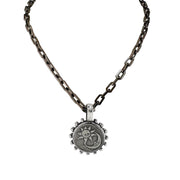 Necklace with a sun coin pendant on an oxidized chain against a white background