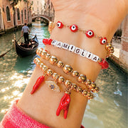 Love Lisa Nicoletta Italian horn protection bracelet styled in a gold bracelet stack with red enamel horn charms and evil eye jewelry