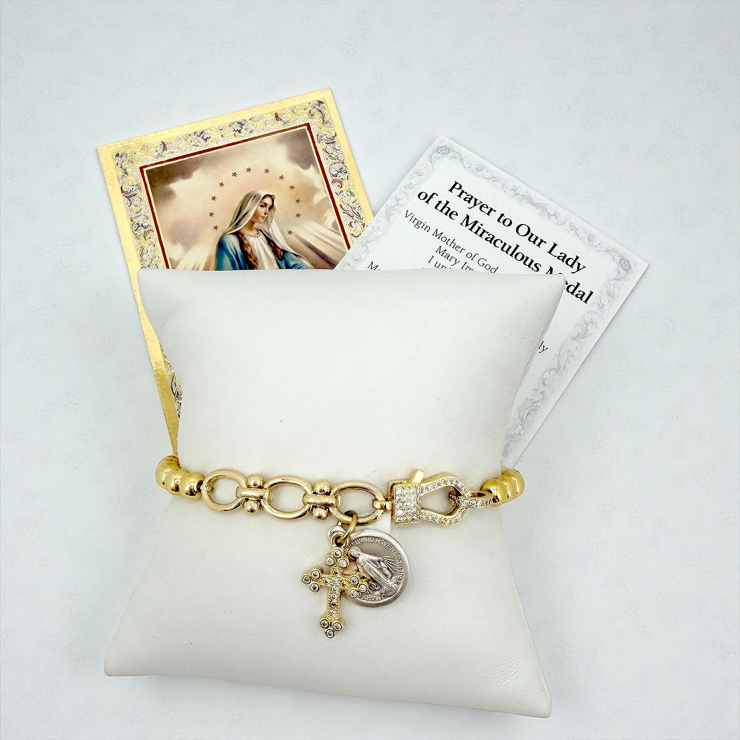 nova sacred link stretch bracelet with miraculous medal on a pillow with prayer card