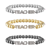 Three 'TEACHER' beaded bracelets in silver, gold, and gray on a white background.