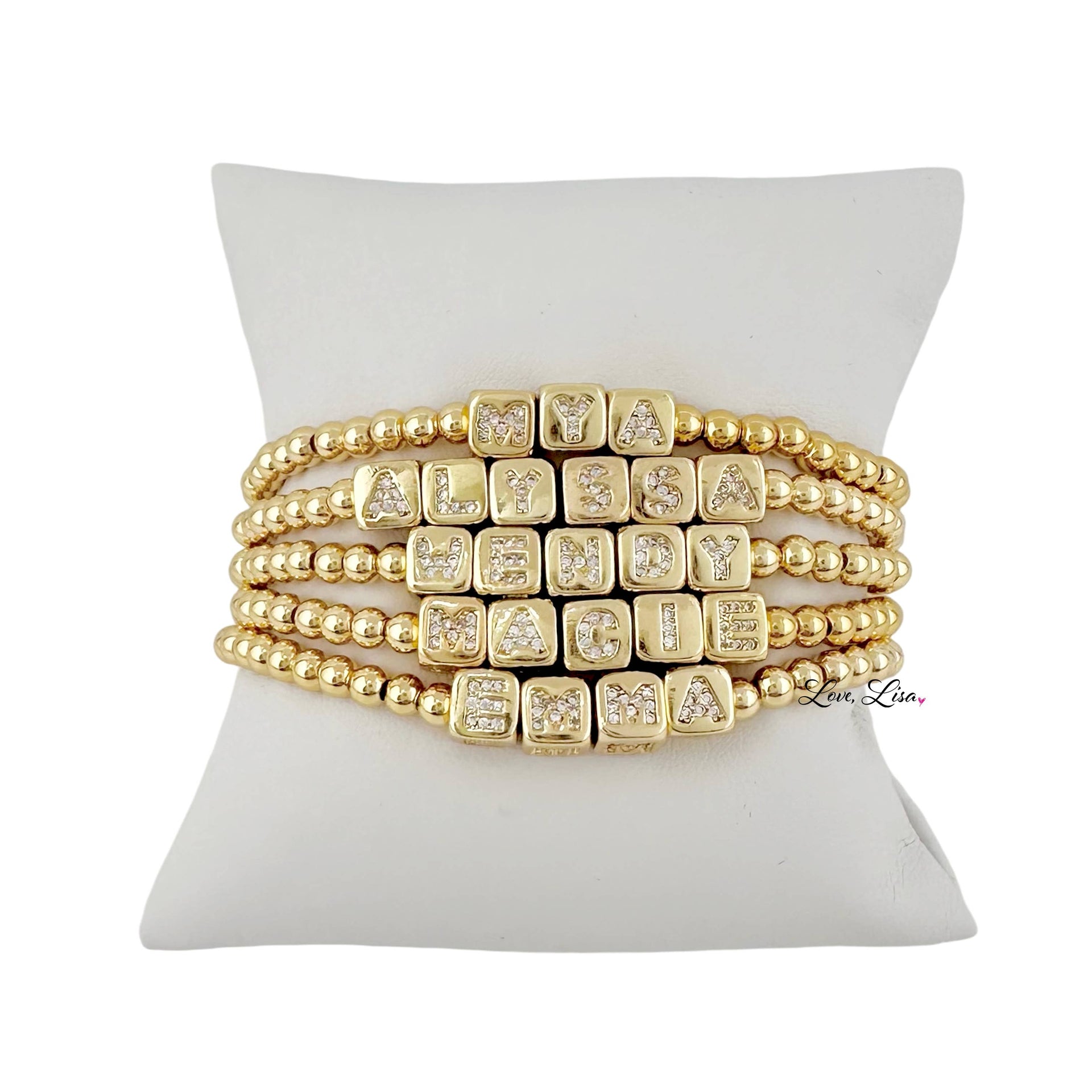 Gold beaded bracelet with square beads on a white cushion