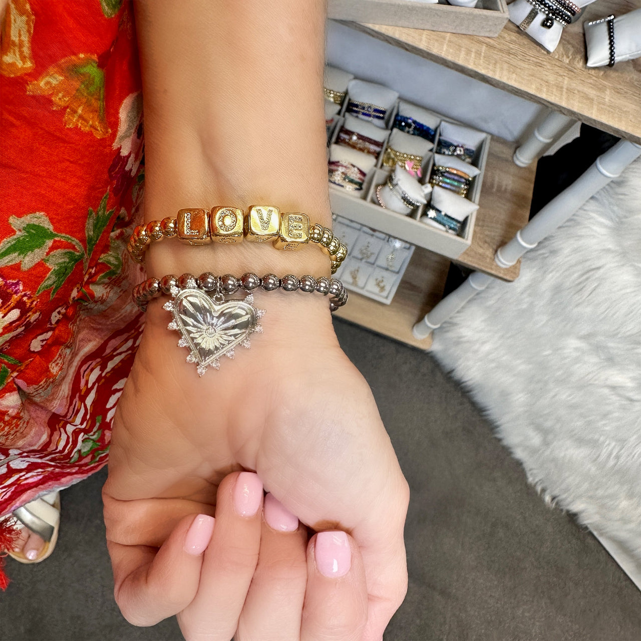  Gold LOVE block letter bracelet stacked with silver beaded heart charm bracelet on wrist