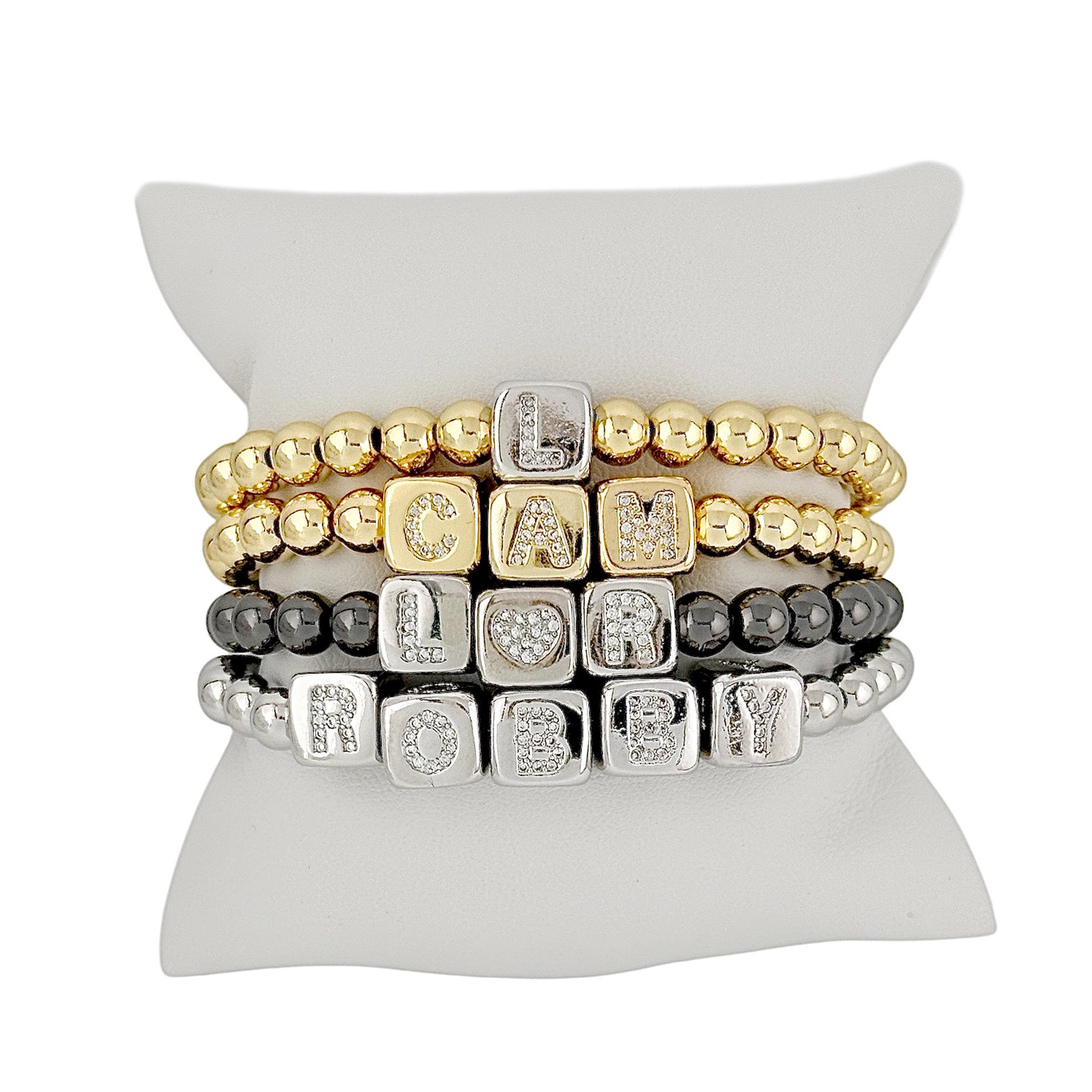 Love Lisa personalized large block letter bracelets displayed on pillow in gold silver and gunmetal stack
