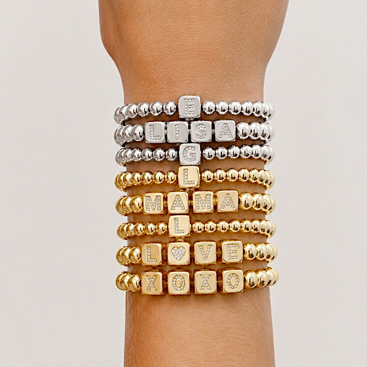 Love Lisa personalized large block letter bracelets stacked on wrist in gold silver and gunmetal bead styles