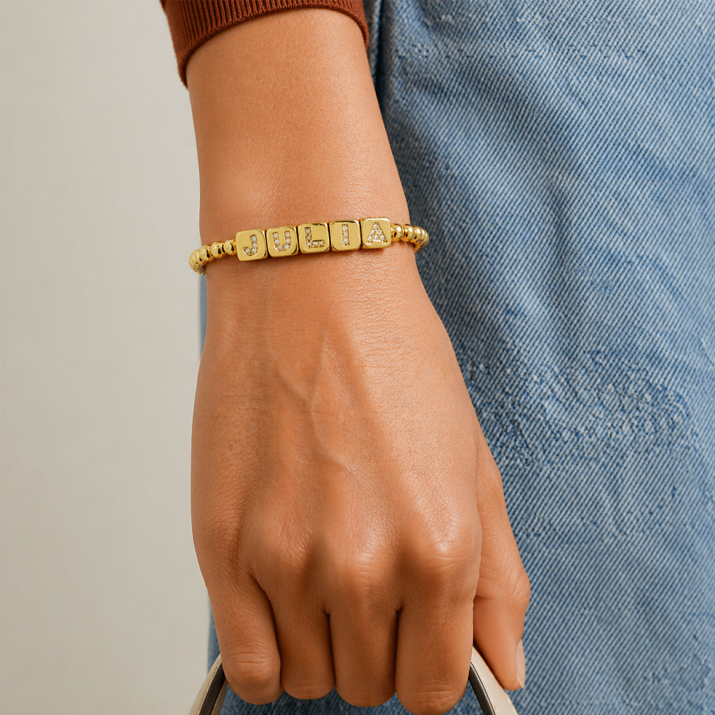 Love Lisa personalized small block letter bracelet worn on wrist with gold beads and petite cube letters