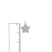 Silver flower-shaped pendant with clear stones next to a ruler on a white background
