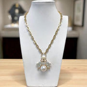 Gold necklace with a pearl pendant on a white mannequin bust.