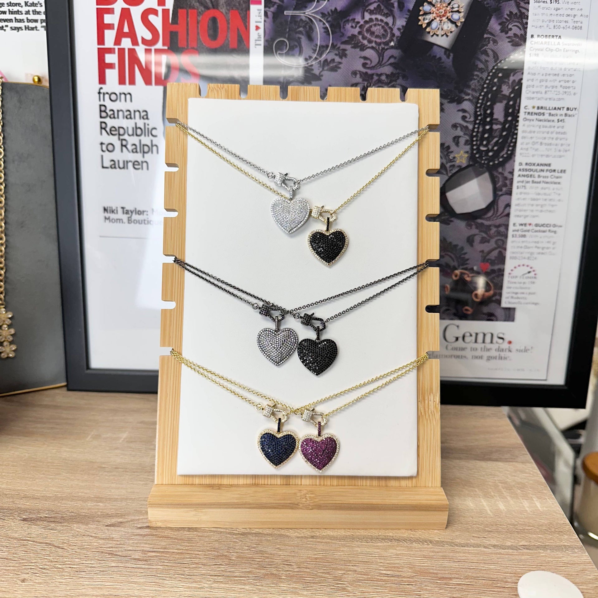Necklace with heart-shaped pendants on a display card against a magazine background