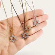 Star-shaped pendants on necklaces held in a hand against a white background