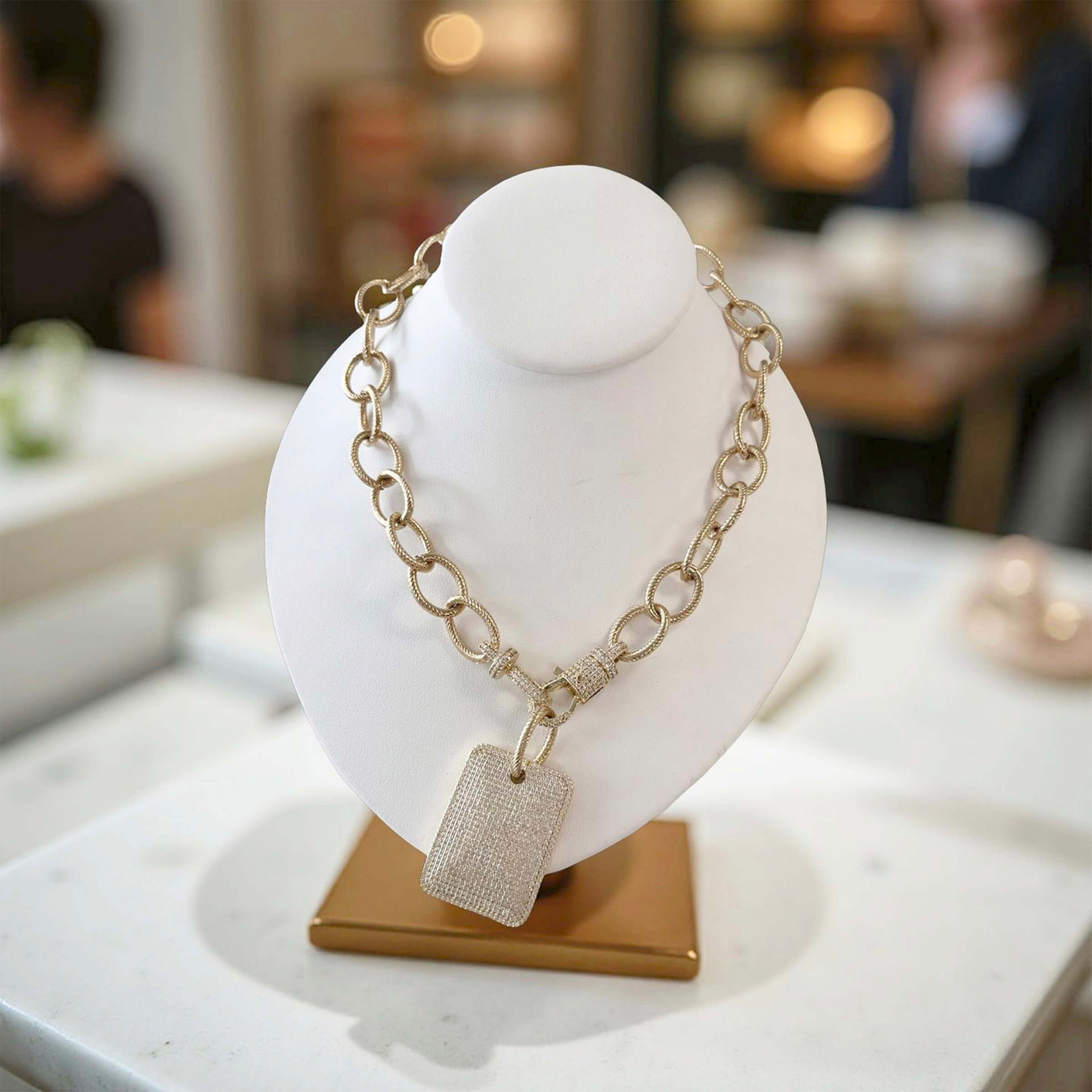 Gold chain necklace with a pendant on a white bust in a store setting