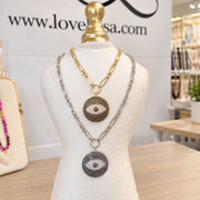 Love Lisa Return to Sender Evil Eye Protection Necklaces displayed in gold and silver finishes with oversized crystal evil eye medallions