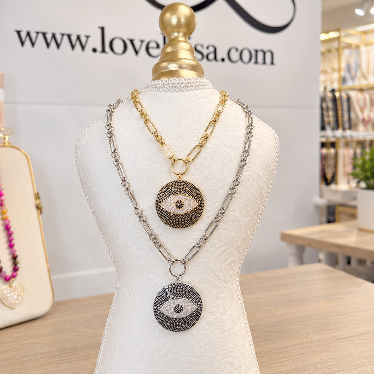 Love Lisa Return to Sender Evil Eye Protection Necklaces displayed in gold and silver finishes with oversized crystal evil eye medallions