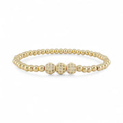 Gold beaded bracelet with three larger gold beads on a white background