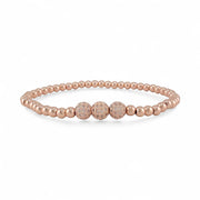 Rose gold beaded bracelet with three glittery beads on a white background