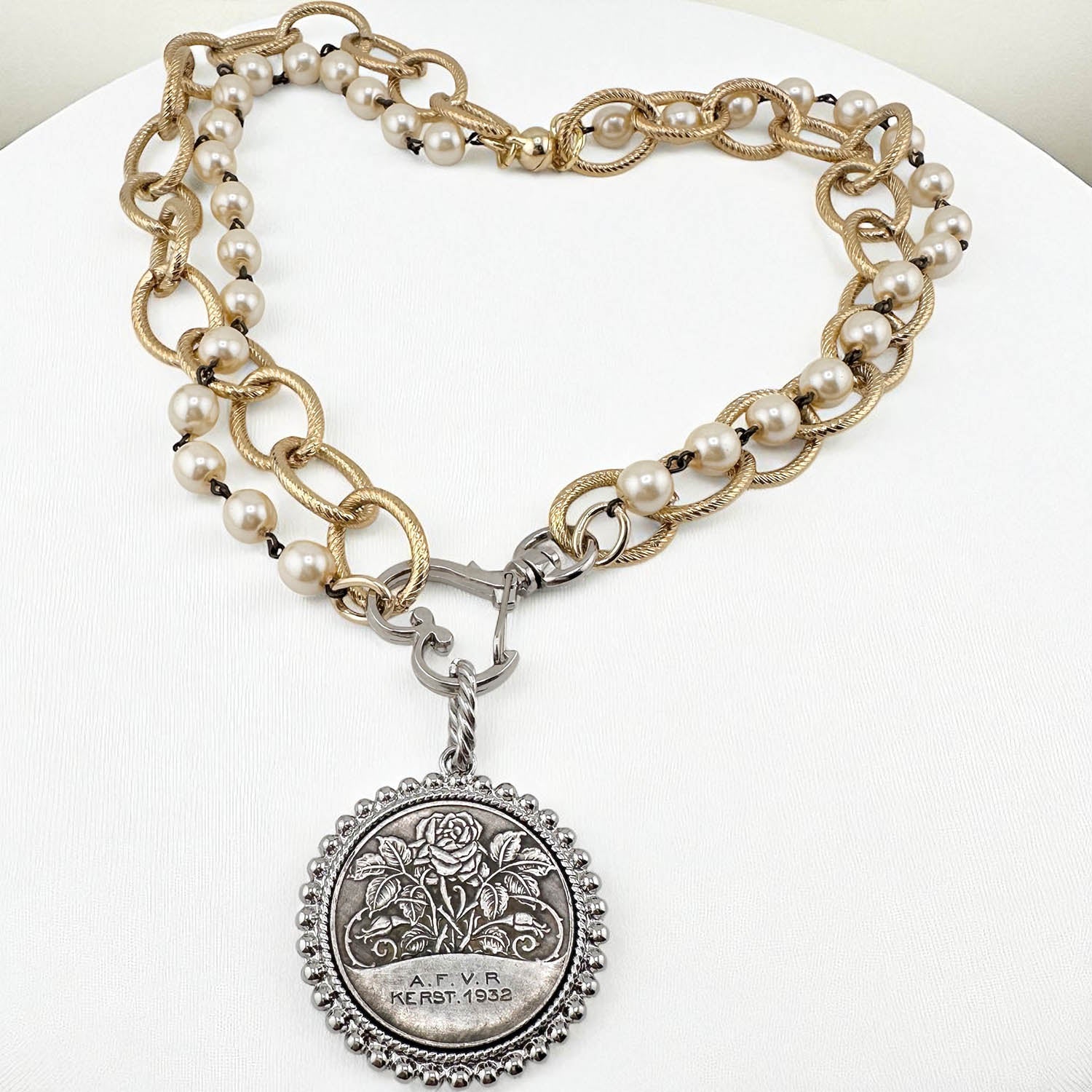 Necklace with pearl and gold chain and silver pendant on a white background