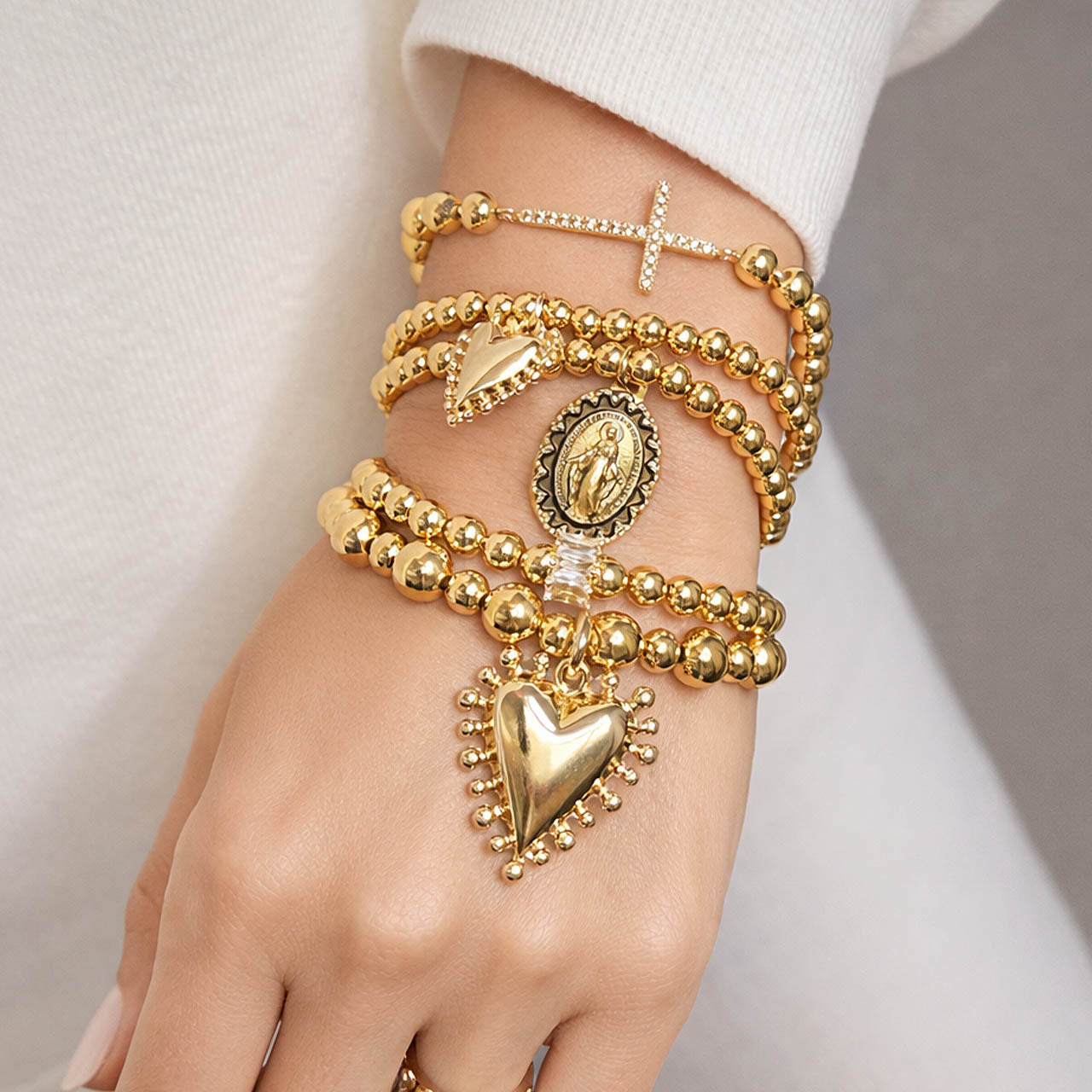 Love Lisa sacred heart blessed mother bracelet stack gold worn layered on wrist five piece faith bracelet set with cross medallion and heart charms