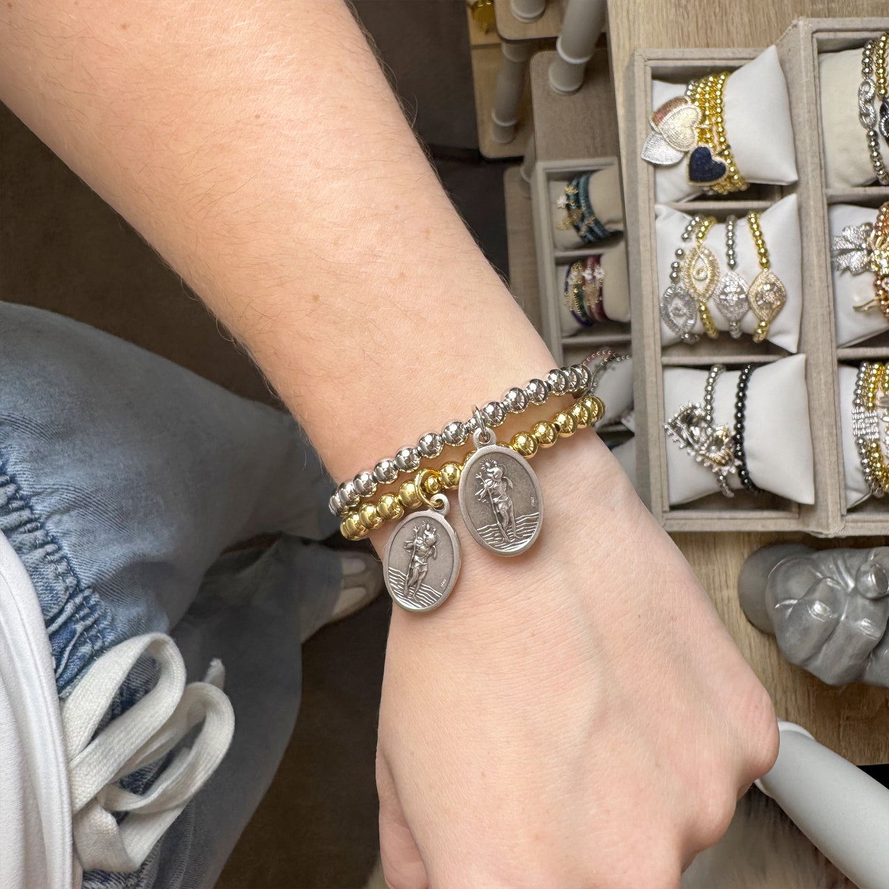 saint christopher driver bracelet stacked on wrist with travel charms

