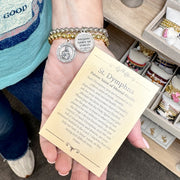 A hand holding the prayer card and 2 saint dymnpha bracelets