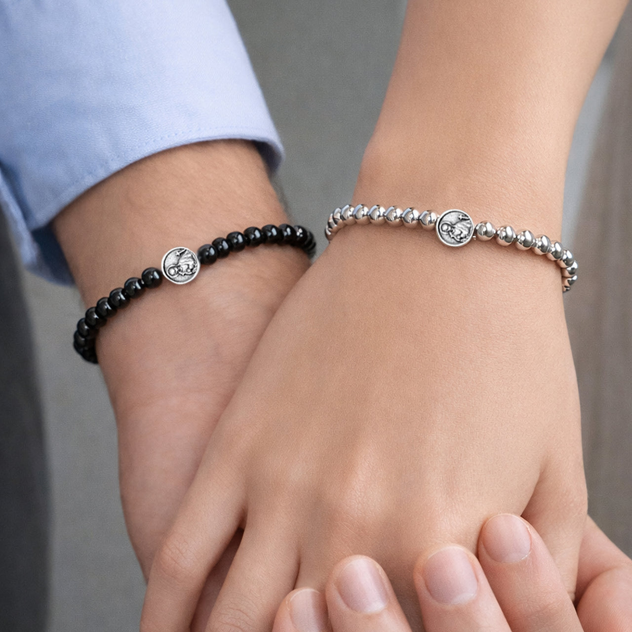 Saint Gerard fertility prayer bracelets worn by couple holding hands