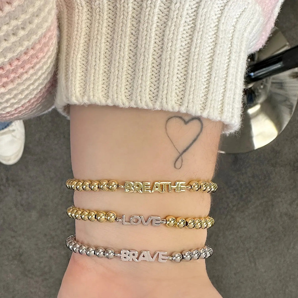 Love Lisa Samantha Breast Cancer Awareness BRAVE Bracelet worn in a mixed metal bracelet stack with polished beads and BRAVE word detail