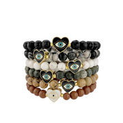 Stack of beaded bracelets with heart-shaped evil eye charms on a white background