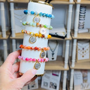 Complete set of five Scarlett Faith gemstone stretch bracelets with Catholic medal charms on a display