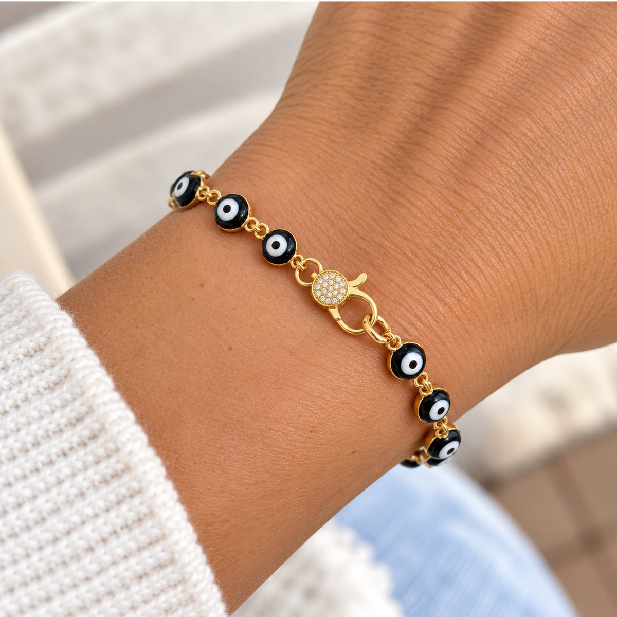 Love Lisa Shari blue evil eye bracelet worn on the wrist with linked blue and white evil eye beads, gold-tone connectors, and crystal pavé clasp