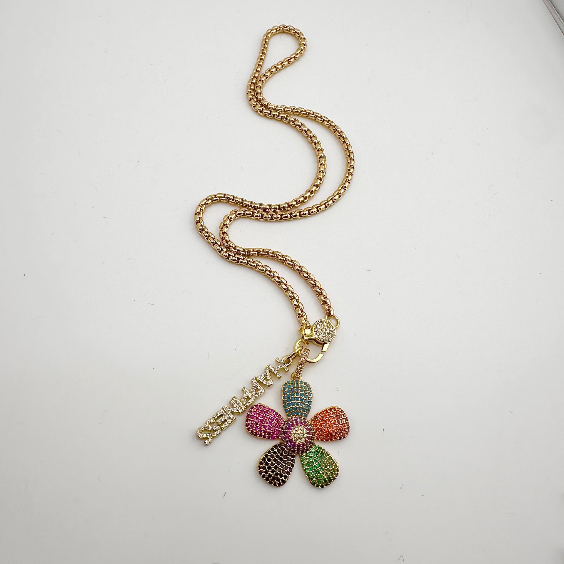shimmering happiness word charm with pave crystals in gold finish on clasp necklace with multicolor pave flower charm