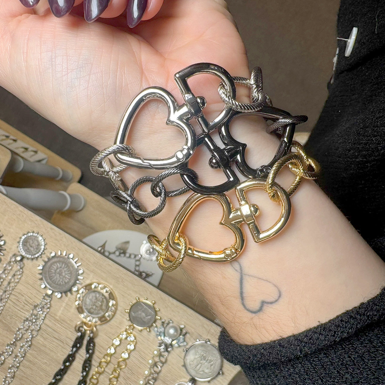 Love Lisa heart clasp chain bracelet styled on wrist layered with statement jewelry