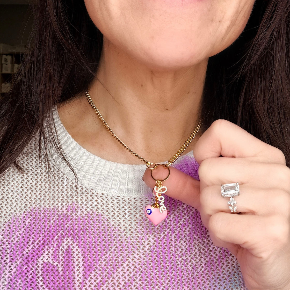 Love Lisa Silvie Breast Cancer Awareness Necklace worn with pink heart charm, evil eye detail, sparkling LOVE charm, and gold-tone chain