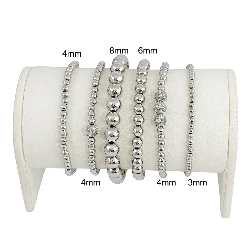 A series of six silver beaded bracelets stacked together, featuring a variety of round beads.