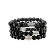 A stack of black bead bracelets with 'SOBER AF' inscribed on one, along with a silver-tone angel charm.