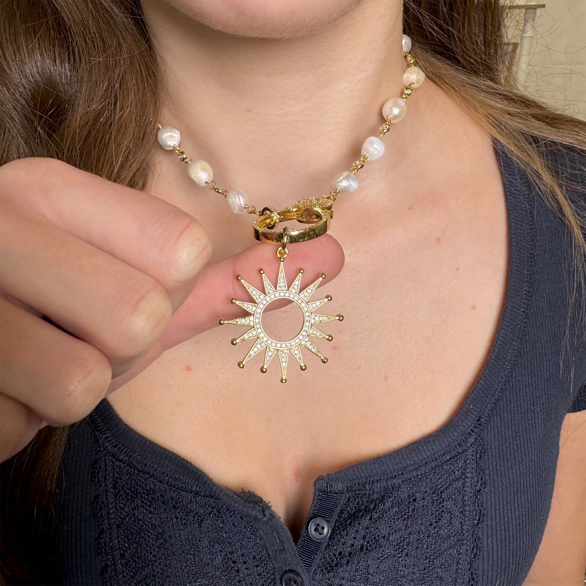 solar sunburst charm in gold worn on pearl clasp necklace